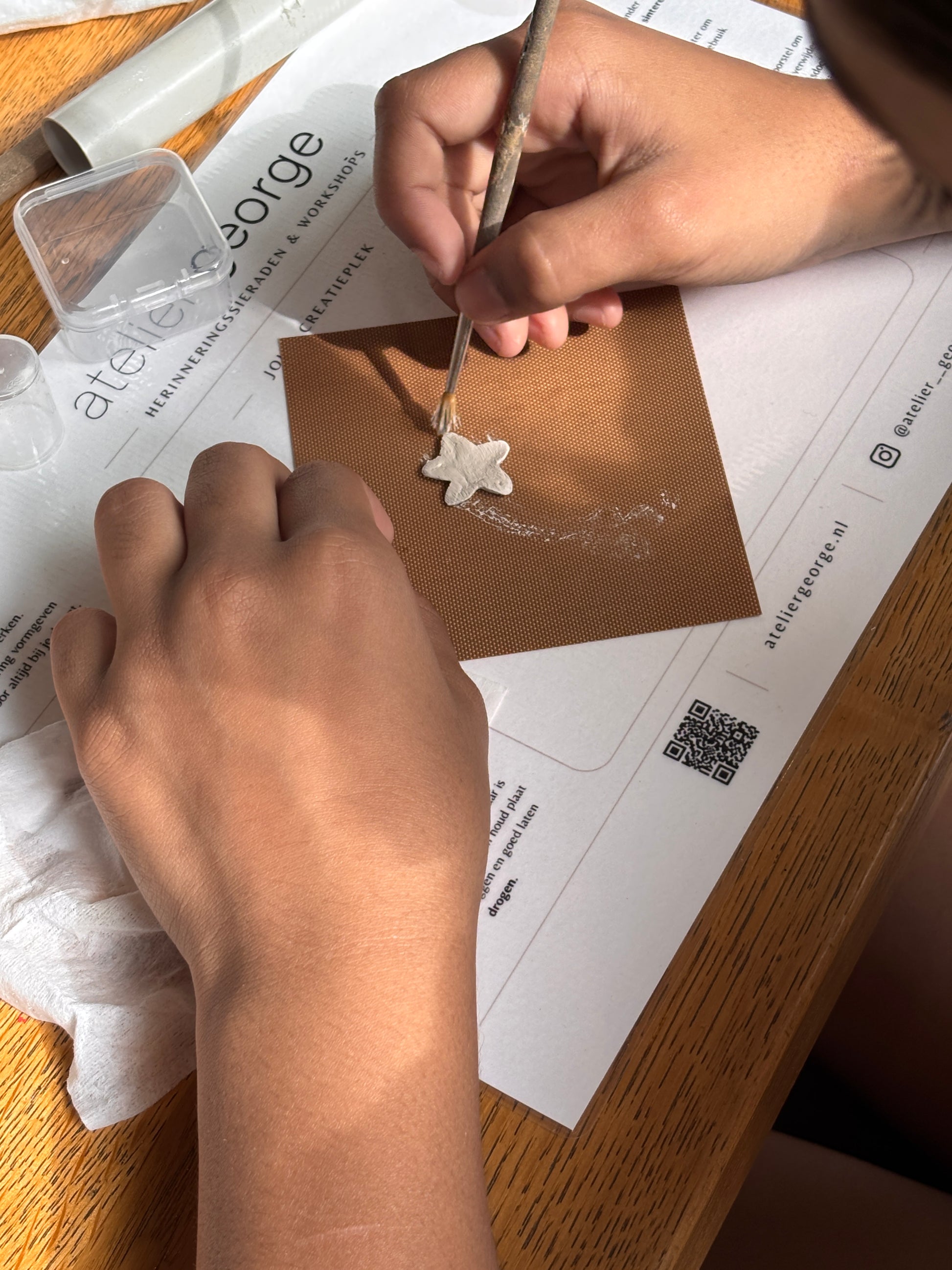 handen met zilverklei hanger aan het maken